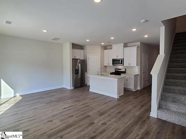 kitchen with a center island with sink, sink, white cabinetry, appliances with stainless steel finishes, and dark hardwood / wood-style flooring