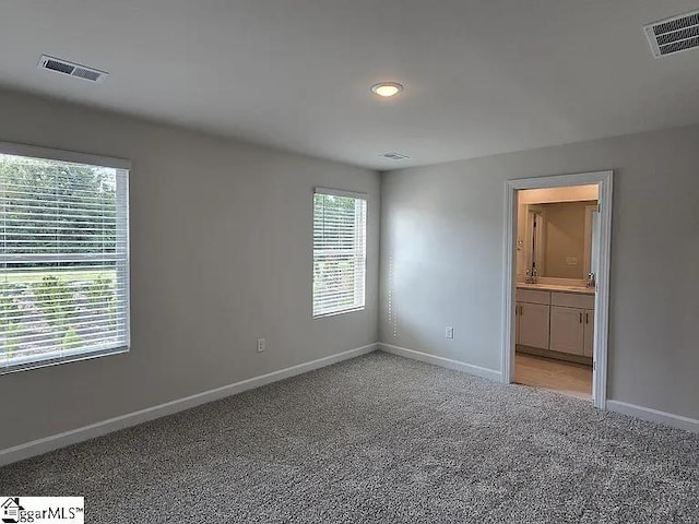 unfurnished bedroom featuring light carpet, sink, and connected bathroom