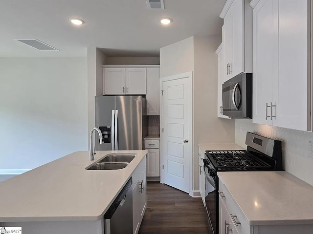 kitchen with stainless steel appliances, white cabinetry, dark hardwood / wood-style flooring, sink, and a kitchen island with sink