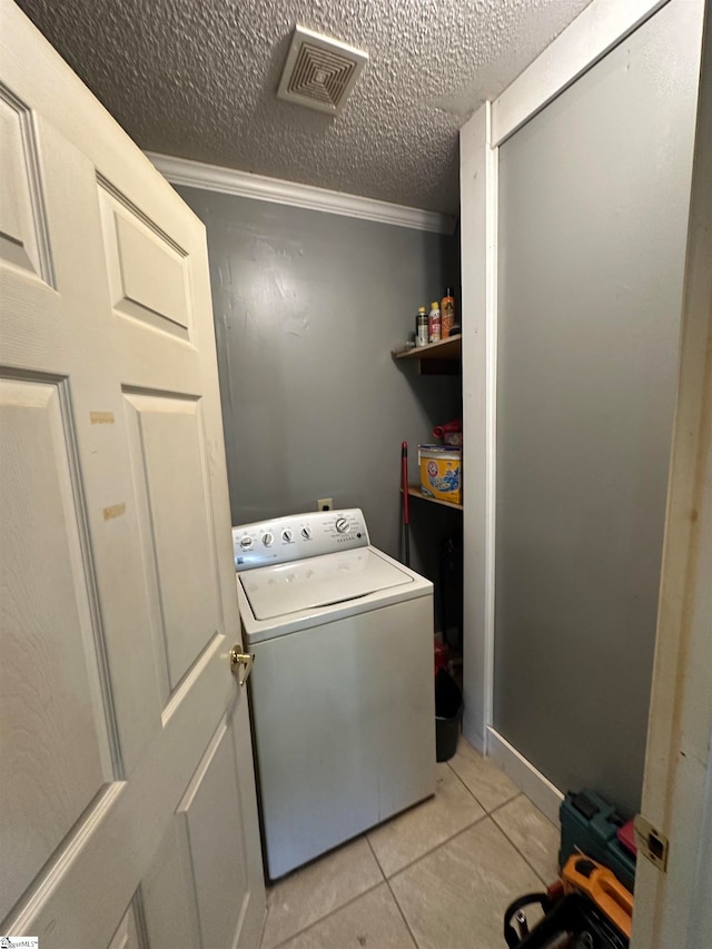 clothes washing area with washer / clothes dryer, a textured ceiling, light tile patterned flooring, and crown molding