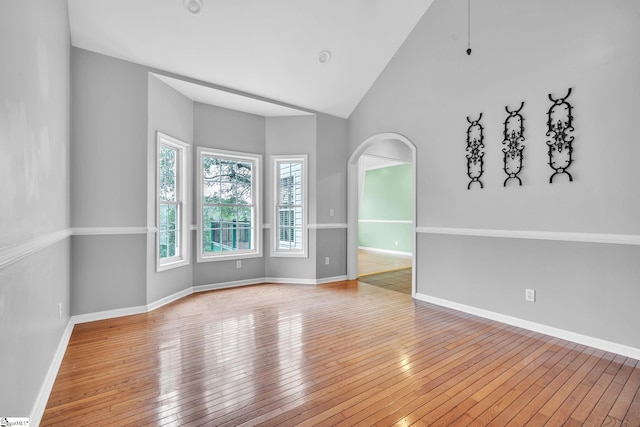 empty room featuring high vaulted ceiling and light hardwood / wood-style floors