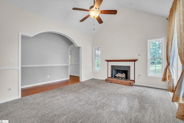 unfurnished living room with high vaulted ceiling, hardwood / wood-style floors, ceiling fan, and a fireplace