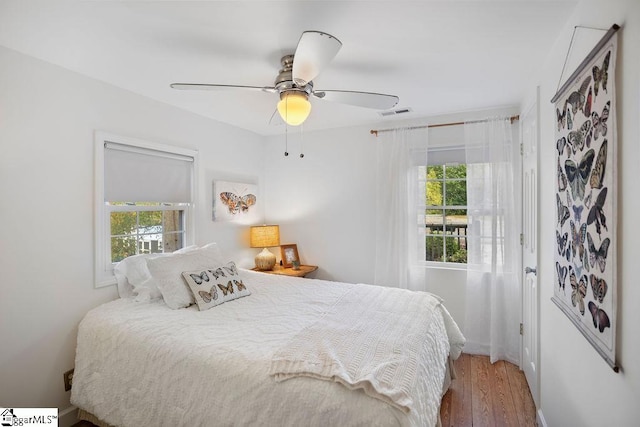 bedroom featuring hardwood / wood-style flooring, ceiling fan, and multiple windows