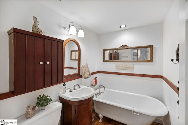 bathroom featuring toilet, a bath, and vanity