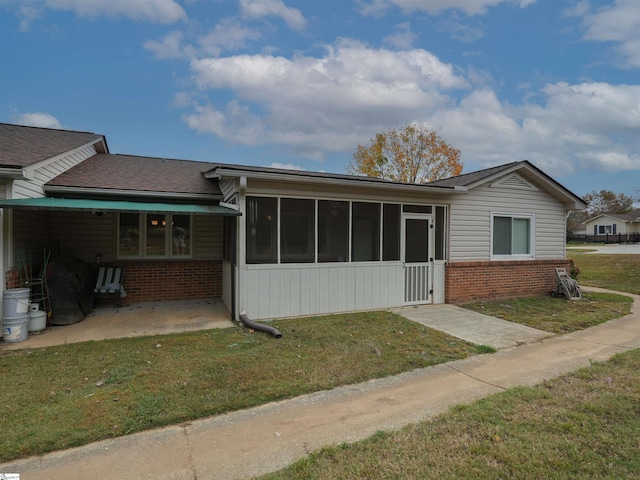 view of front facade with a patio area, a sunroom, and a front lawn