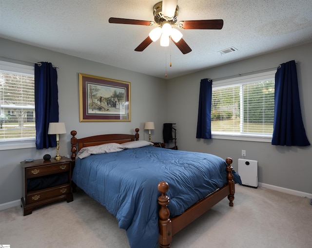 bedroom with ceiling fan, a textured ceiling, and light colored carpet