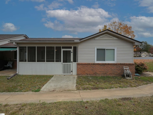 view of front facade with a sunroom and a front lawn