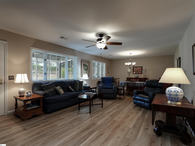 living room with light hardwood / wood-style floors and ceiling fan with notable chandelier