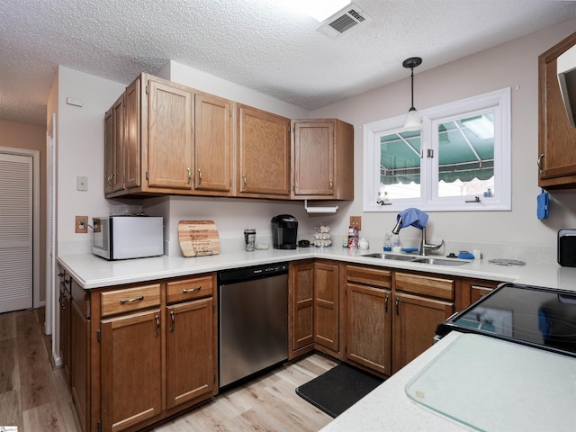 kitchen with light wood-type flooring, a textured ceiling, pendant lighting, sink, and dishwasher