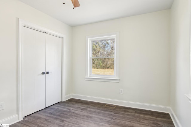 unfurnished bedroom featuring dark wood-type flooring, ceiling fan, and a closet