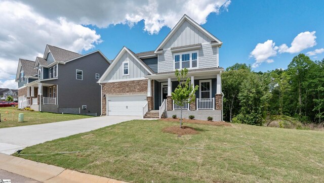 craftsman inspired home with board and batten siding, covered porch, concrete driveway, a front yard, and an attached garage