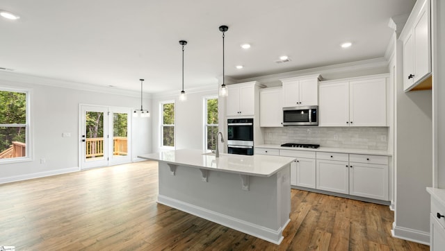 kitchen featuring stainless steel appliances, crown molding, backsplash, light countertops, and plenty of natural light