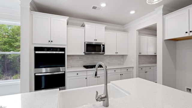 kitchen featuring stainless steel appliances, a sink, white cabinets, decorative backsplash, and recessed lighting