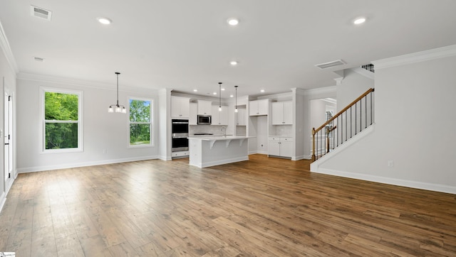 unfurnished living room with ornamental molding, baseboards, stairway, wood-type flooring, and recessed lighting