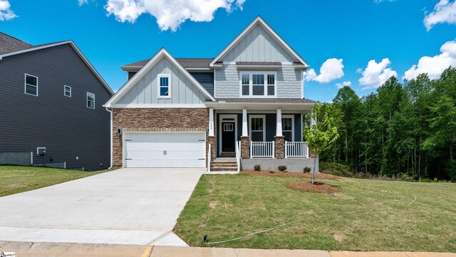 craftsman-style house featuring board and batten siding, covered porch, driveway, an attached garage, and a front lawn