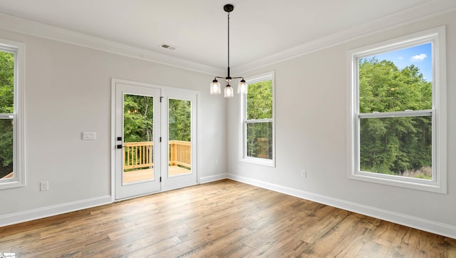 unfurnished dining area featuring baseboards, hardwood / wood-style flooring, crown molding, and a chandelier