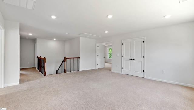 carpeted empty room featuring baseboards, attic access, and recessed lighting