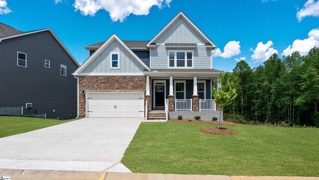 craftsman inspired home featuring board and batten siding, a porch, driveway, a front yard, and a garage