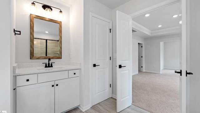 bathroom featuring vanity, a tray ceiling, recessed lighting, baseboards, and ornamental molding