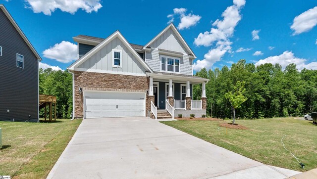 craftsman-style home with covered porch, board and batten siding, stone siding, driveway, and a front lawn