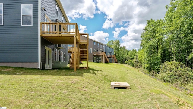 view of green lawn featuring stairs and a deck