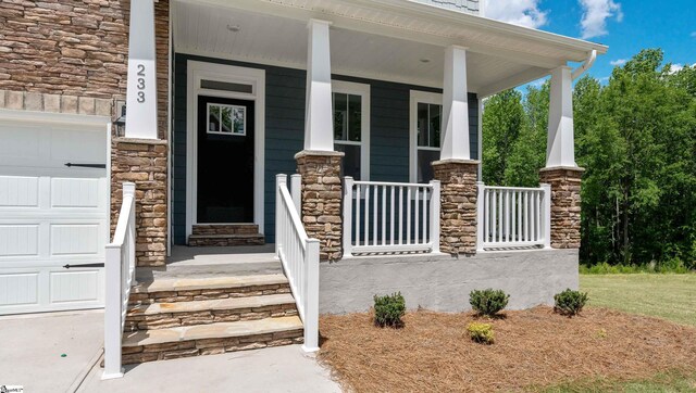 doorway to property featuring a porch, stone siding, and an attached garage