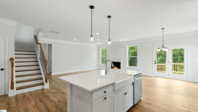 kitchen featuring a sink, open floor plan, dishwasher, light countertops, and ornamental molding