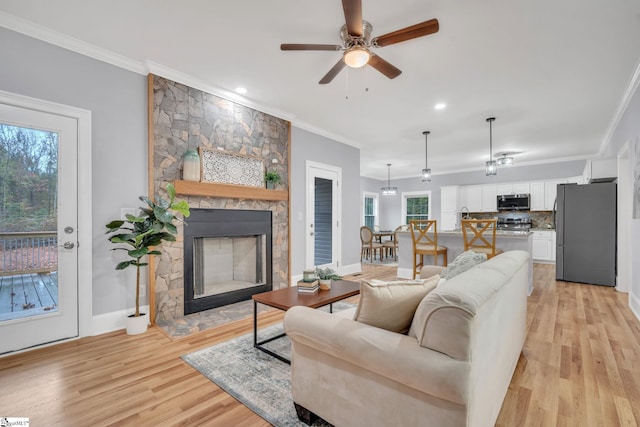 living room with crown molding, light hardwood / wood-style floors, and plenty of natural light