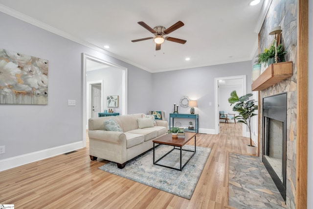 living room featuring a fireplace, light hardwood / wood-style floors, and crown molding