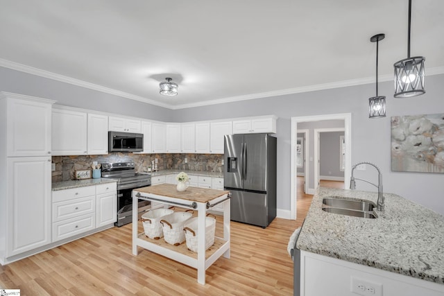 kitchen with stainless steel appliances, white cabinetry, pendant lighting, sink, and light hardwood / wood-style flooring