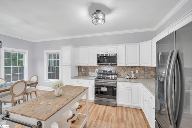 kitchen with white cabinets, stainless steel appliances, light stone counters, and light hardwood / wood-style flooring