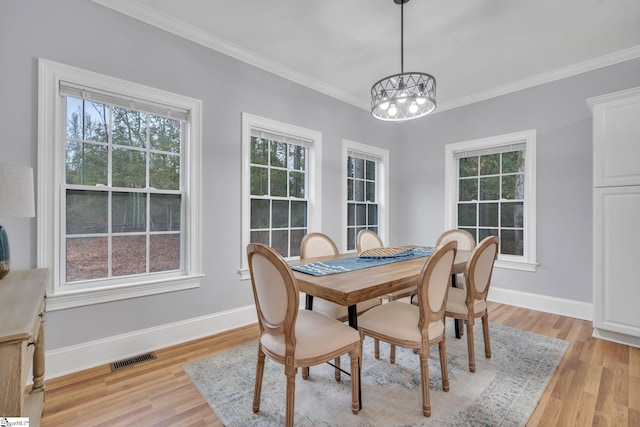 dining room with a notable chandelier, ornamental molding, and light hardwood / wood-style flooring