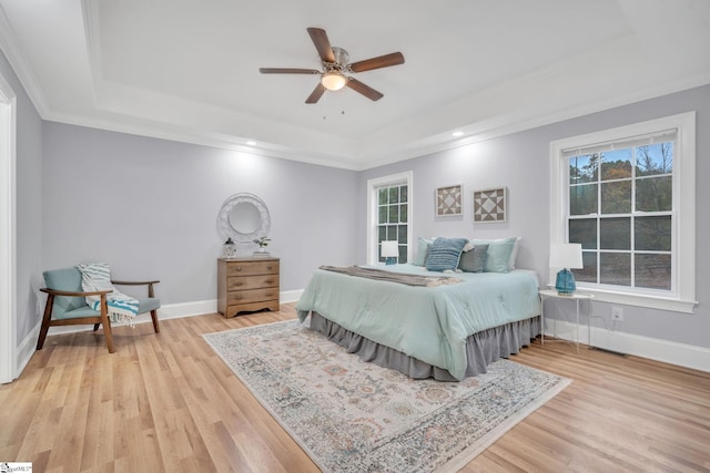 bedroom with ceiling fan, a raised ceiling, light hardwood / wood-style flooring, and ornamental molding