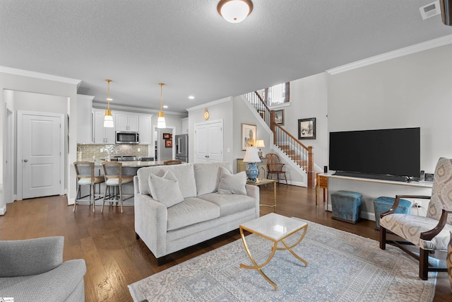 living room featuring dark hardwood / wood-style floors, a textured ceiling, and ornamental molding