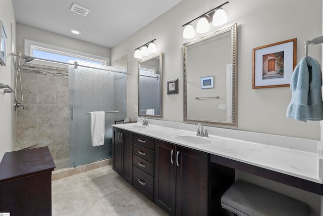 bathroom with walk in shower, vanity, a textured ceiling, and tile patterned floors