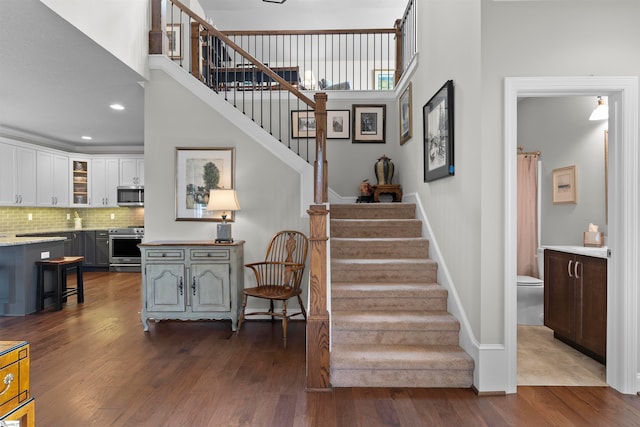 staircase with hardwood / wood-style flooring and a towering ceiling