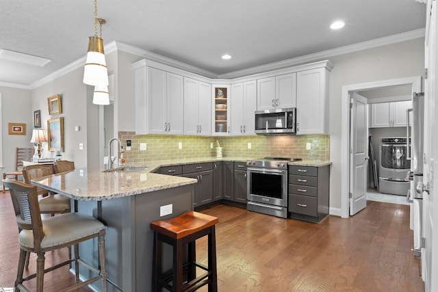 kitchen with stainless steel appliances, white cabinets, hanging light fixtures, a breakfast bar area, and dark hardwood / wood-style floors