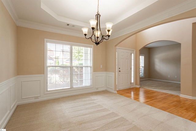 unfurnished room with a chandelier, a raised ceiling, light hardwood / wood-style flooring, and crown molding