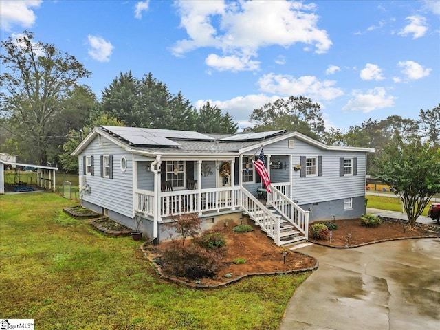 view of front facade with a front lawn, solar panels, and covered porch