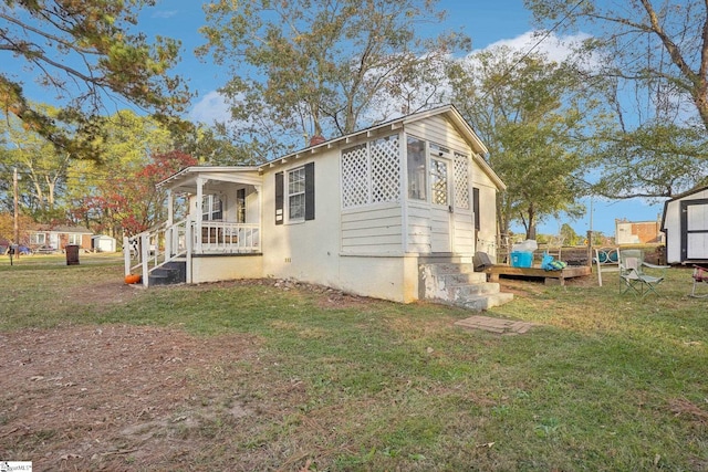 view of side of home with a porch, a lawn, and a shed