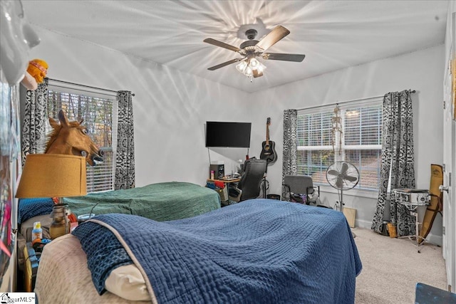 carpeted bedroom featuring multiple windows and ceiling fan