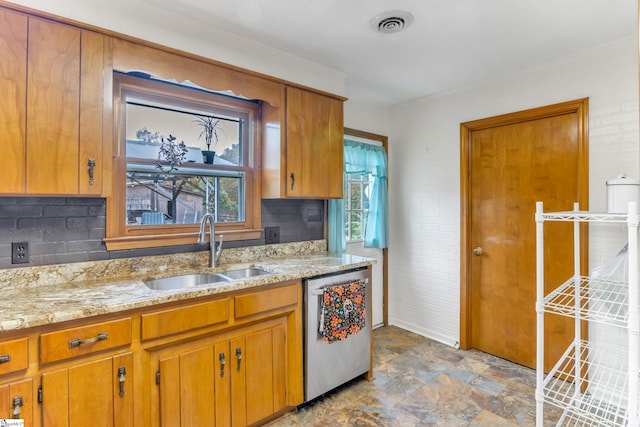 kitchen with stainless steel dishwasher, sink, backsplash, and light stone countertops