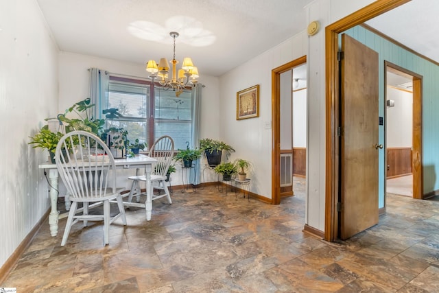 dining area featuring wooden walls, an inviting chandelier, and crown molding