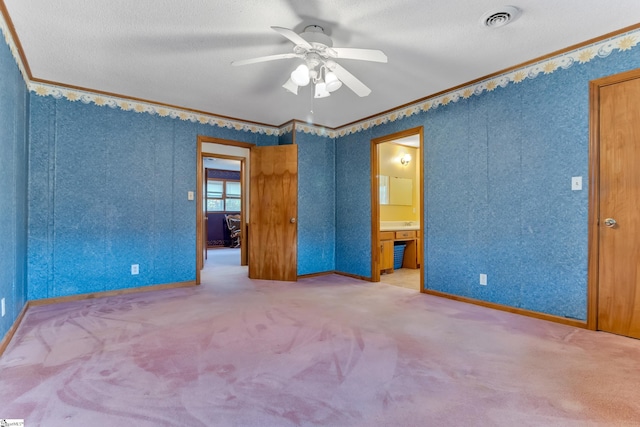 unfurnished bedroom featuring carpet flooring, ensuite bathroom, ornamental molding, and ceiling fan