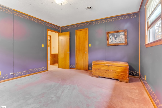 unfurnished bedroom featuring carpet, a textured ceiling, and ornamental molding