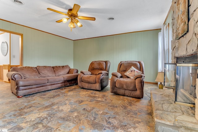 living room featuring ornamental molding, wood walls, and ceiling fan