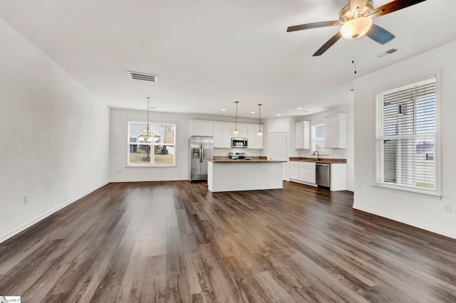 unfurnished living room featuring dark wood-type flooring, sink, and ceiling fan with notable chandelier