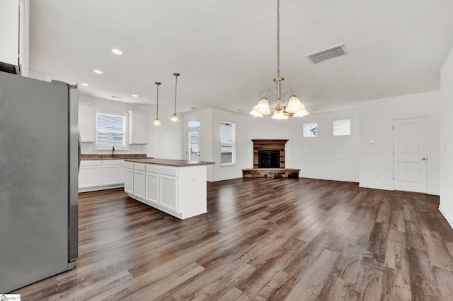 kitchen with decorative light fixtures, a kitchen island, wood-type flooring, and stainless steel fridge