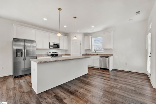 kitchen featuring stainless steel appliances, dark hardwood / wood-style floors, pendant lighting, white cabinets, and a center island