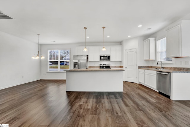 kitchen featuring dark hardwood / wood-style floors, a kitchen island, pendant lighting, appliances with stainless steel finishes, and white cabinetry